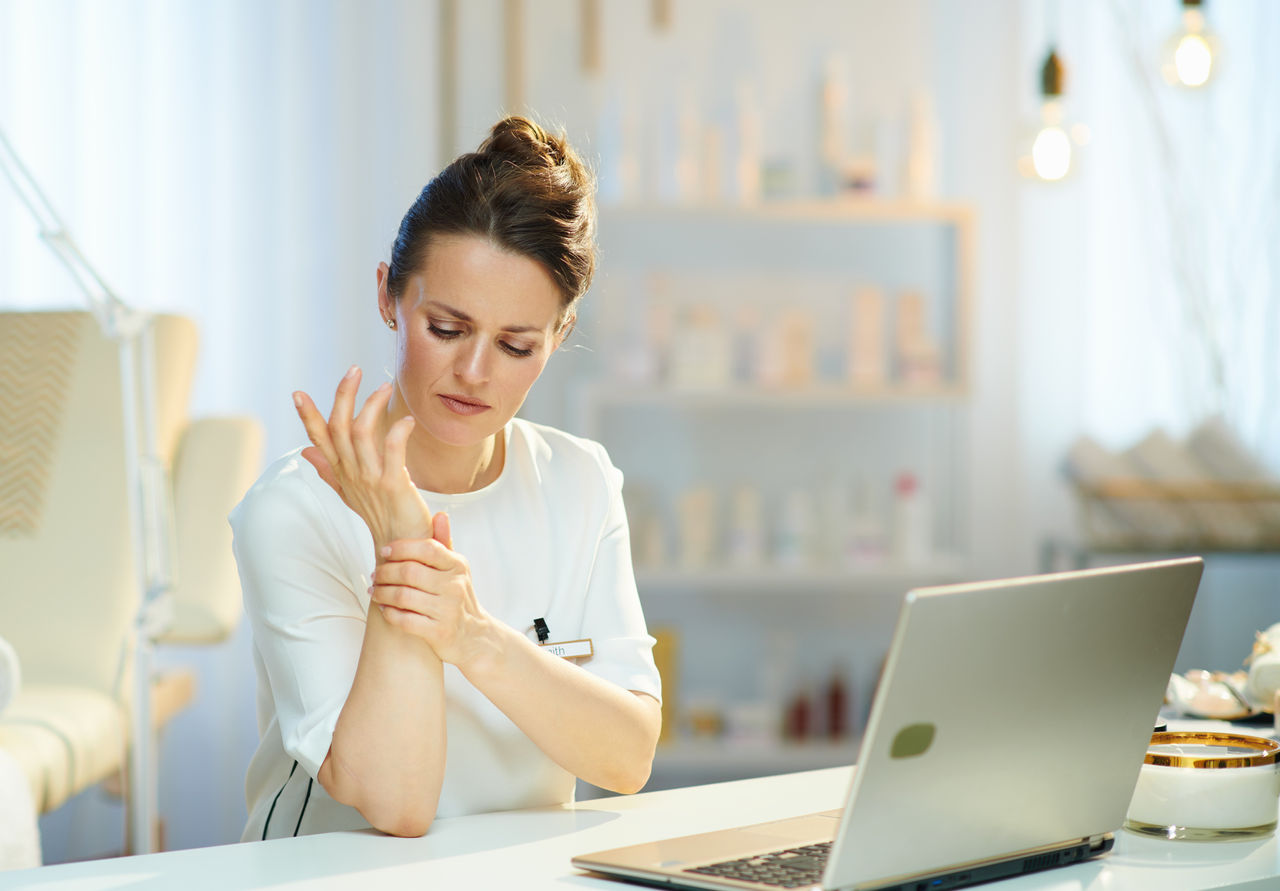 tired woman worker having wrist pain in modern beauty salon